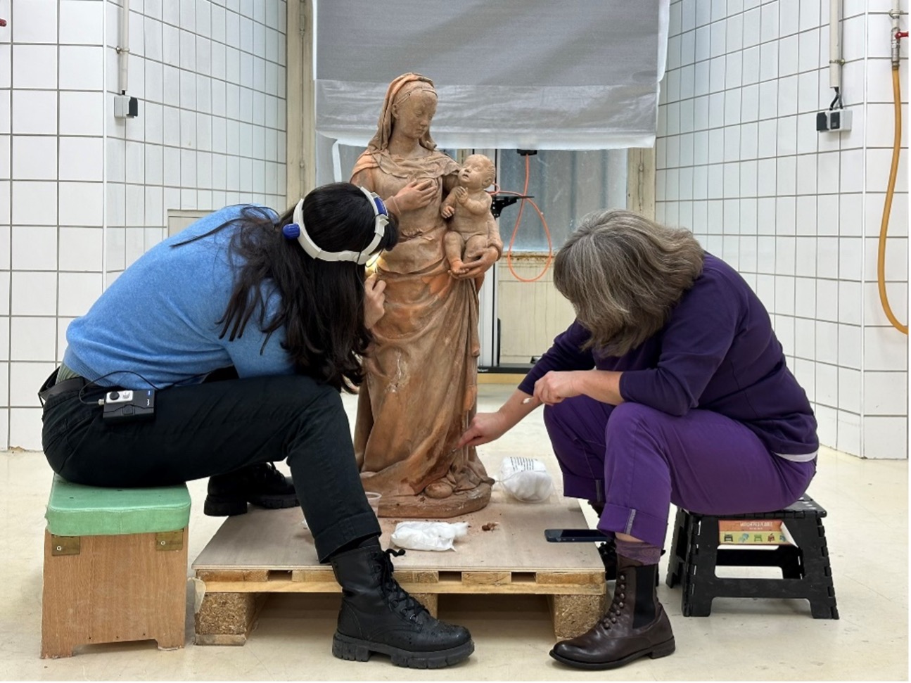 L’œuvre en cours de nettoyage par Hélène Susini et Azzurra Palazzo : les parties restituées (éléments du voile et du drapé de la Vierge, bras droit de la Vierge, mains du Christ) apparaissent en orange vif.
